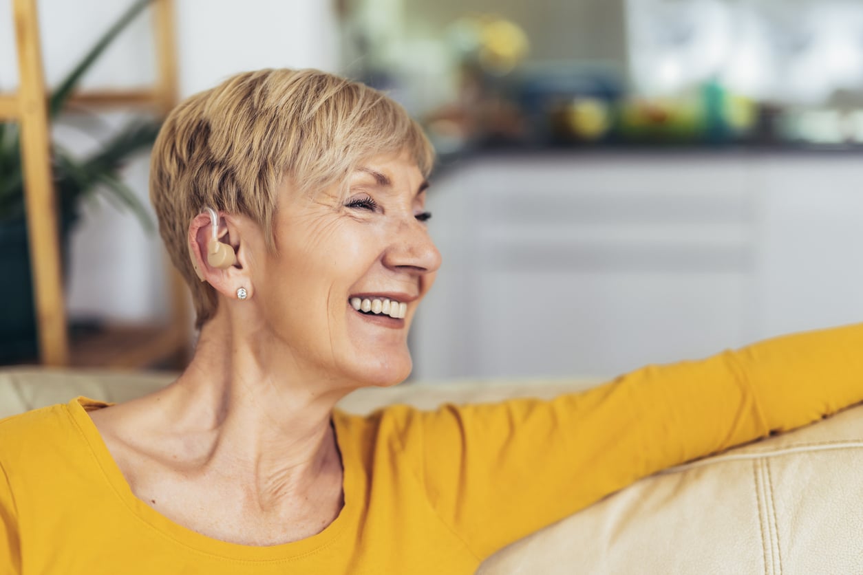 woman with hearing loss smiles on couch