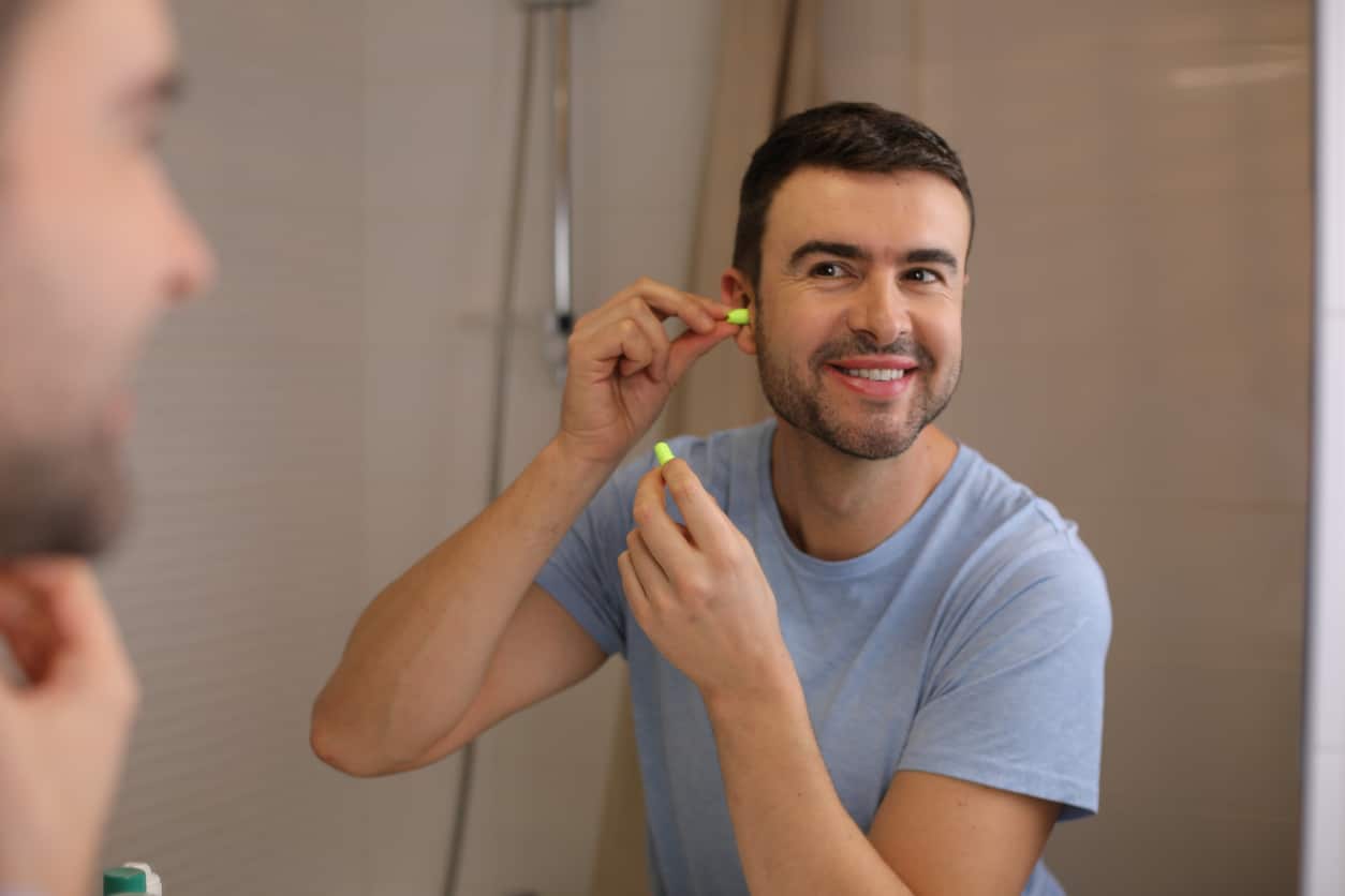 Man wears earplug to protect hearing