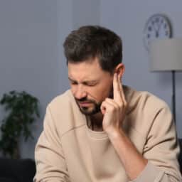 Man holding his ear experiencing misophonia