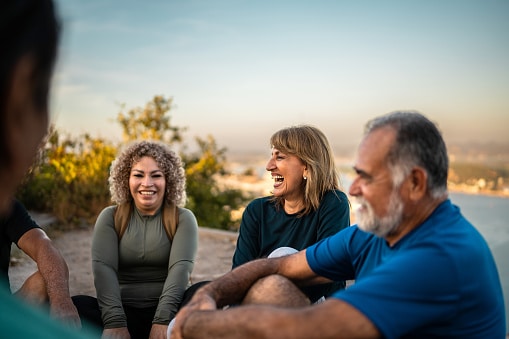 Group of friends chatting and laughing on the beach.