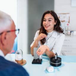 Audiologist shows off the latest hearing aid technology to her patient at a hearing aid consultation and hearing evaluation.