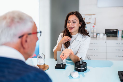 Audiologist shows off the latest hearing aid technology to her patient at a hearing aid consultation and hearing evaluation.